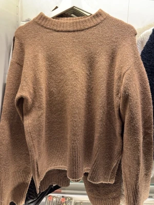 Brun stickad tröja från Kappahl - Mysig brun stickad tröja från Kappahl i storlek XS. Tröjan har en avslappnad passform, ribbade muddar och en bred ribbad kant nertill. Perfekt för lager-på-lager under kyliga dagar.