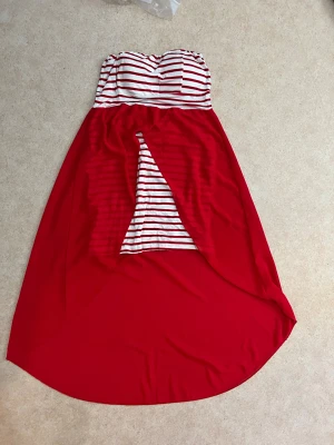 Randig långklänning (s) - Säljer en fin klänning  med röd och vit randig överdel och röd kjol med slits framtill. Klänningen är axelbandslös. 