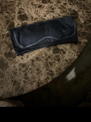 Svart tubtopp i stretchigt tyg - Snygg svart tubtopp i ett stretchigt och mjukt material. Enkel och stilren design med diskreta sömmar som ger en cool look. Perfekt att matcha med jeans eller kjol för en trendig outfit.