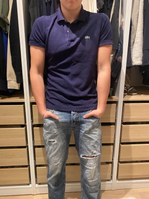 Mörkblå Lacoste piké  - Säljer en mörkblå Lacoste piké, säljer eftersom den är för lång för mig.
