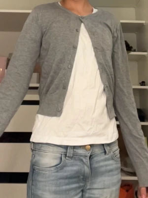 Grå croppad kofta  - Snygg grå croppad kofta som aldrig är andvänd, från H&M. Är 165 och den sitter bra, den är dock croppad så den är ganska kort.