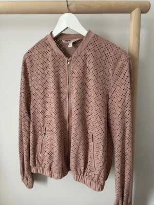 Rosa bomberjacka från Zara - Säljer en rosa bomberjacka från Zara i storlek M. Jackan har ett prickigt mönster med små hål, dragkedja framtill och två fickor med dragkedja. Materialet känns som mocka och har en mjuk finish. 