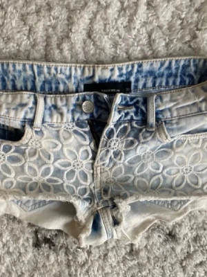 Blommiga jeansshorts från Tally Weijl - Inte mina bilder! Snygga ljusblå jeansshorts från Tally Weijl med blommigt broderi framtill och råa kanter. Köptes här på plick för 375 o bara använda en gång under kort tid av mig, därför priset.  Midjemåttet är 36 och det är inte jättestretchigt tyg, men sjukt snygga💗 snygg design där fram också💞