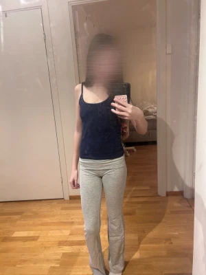 Grå mjukisbyxor med bootcut - Säljer ett par ljusgrå mjukisbyxor med bootcut och låg midja. Byxorna är i mjukt bomullsmaterial och har en bekväm passform som sitter tajt upptill och släpper ut vid benen. Perfekta för en chill och avslappnad stil.