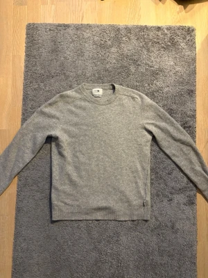 Grå stickad tröja från NN07 - Säljer en stilren grå tröja från NN07 i 100% ull. Använd max 5 gånger, i princip ny. Modell Edward, tillverkad av italienskt garn.