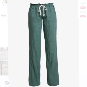 Gröna linnebyxor från Roxy med snörning - Snygga gröna linnebyxor från Roxy med avslappnad passform och bred resår i midjan. Byxorna har vit snörning framtill, raka ben och praktiska fickor både fram och bak. Perfekta för chill dagar eller när du vill ha en skön stil.