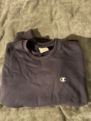 Champion sweatshirt  - Champion sweatshirt i marinblå färg. Tröjan är i storlek S men är sydd i botten( kan tas bort). Köpt på stadium, pris kan diskuteras👍