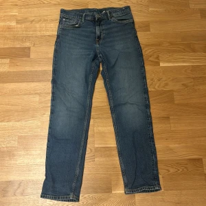 Blå slim fit jeans från H&M, stl 158 - Snygga blå jeans från H&M i slim fit-modell med justerbar midja. Klassisk femficksdesign, raka ben och diskreta slitningar. Perfekta för dig som gillar en enkel och stilren look. Passar dig som är ca 12-13 år.