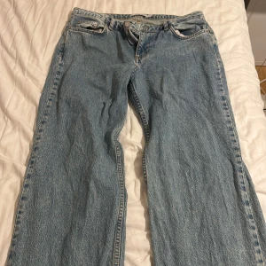Blå wide jeans från NA-KD, stl 38 - Säljer ett par ljusblå jeans från NA-KD i storlek 38. Modellen har en rak och wide passform mid waist midja och råa, slitna benslut. Klassisk femficksdesign och tillverkade i jeansmaterial. 