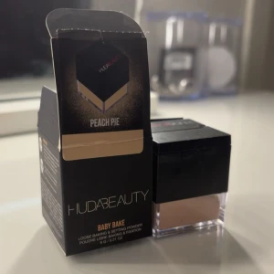 Huda Beauty Baby Bake Peach Pie puder - Loose baking & setting powder i nyansen Peach Pie från Huda Beauty. Kommer i en stilren fyrkantig burk med svart lock och transparent botten. Perfekt för att fixera sminket och ge en matt finish. Innehåller 6g puder. Pudret är öppnat men helt fullt, bara använd en gång för att se färgen. ❤️
