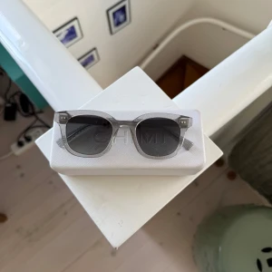 Grå solglasögon från CHIMI - Säljer ett par stilrena solglasögon från CHIMI med transparent grå båge och runda linser. Kommer i original vit CHIMI-fodral. 