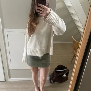 Olivgrön jeanskjol med rå kant - Säljer en olivgrön kort jeanskjol med rå, fransig kant nertill och klassiska fickor fram och bak. Kjolen har knapp och dragkedja framtill och är perfekt för dig som gillar en avslappnad och trendig stil.