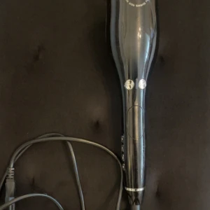 Automatisk elektron locktång  - Automatisk elektron locktång i svart med sladd. Utrustad med knappar för inställningar och enkel hantering. Produkten är i gott skick utan synliga repor eller skador. Perfekt för snabb och smidig hårstyling hemma.