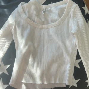 Vit ribbad långärmad topp H&M Divided - Säljer en vit ribbad långärmad topp från H&M Divided. Toppen har en rundad halsringning och är tillverkad i ett mjukt, stretchigt material som sitter snyggt på kroppen. Perfekt att styla med jeans eller kjol för en clean look.
