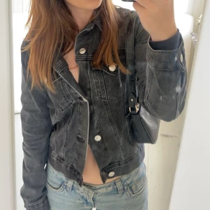 Svart jeansjacka med silvriga knappar - Säljer en svart jeansjacka med snygg tvätt och silvriga knappar. Klassisk modell med krage, bröstfickor och långa ärmar. 