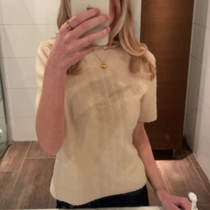 Beige stickad kortärmad tröja - Säljer en supermjuk och stilren beige stickad tröja med korta ärmar. Perfekt för lager-på-lager och funkar lika bra till jeans som till kjol. Enkel och klassisk design med rund halsringning och ribbade kanter.💕