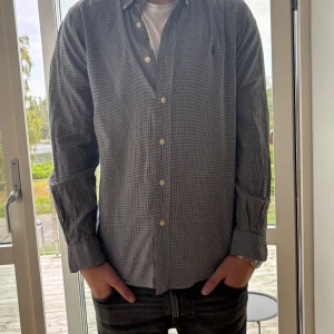 Rutig skjorta från Ralph Lauren S - Snygg rutig skjorta från Ralph Lauren i svart och vitt. Klassisk button-down med broderad logga på bröstet, långa ärmar och knappar framtill. Skjortan är i bomull och har en tidlös, clean look som passar perfekt till jeans.
