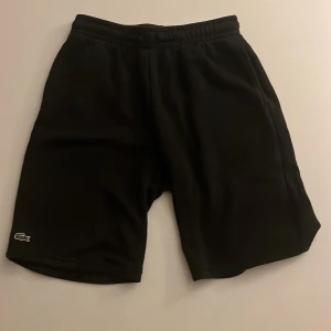 Svarta shorts från Lacoste  - Snygga svarta shorts från Lacoste perfekta för en sportig look. Elastisk midja för extra komfort.