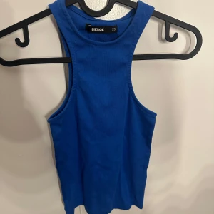 Blå linnetopp från BikBok XS - Snygg blå linnetopp från BikBok i storlek XS. Toppen har en klassisk rak modell med breda axelband och rund halsringning. Perfekt att matcha med jeans eller kjol för en fräsch look. Tillverkad i mjuk bomull som känns skön mot huden