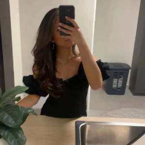 Svart offshoulder kortklänning - Supersnygg svart kortklänning med offshoulder och puffiga ärmar. Klänningen har en figurnära passform och är tillverkad i ett slätt tyg som ger en stilren look. Perfekt för dig som vill ha en trendig och elegant outfit med lite edge.💓