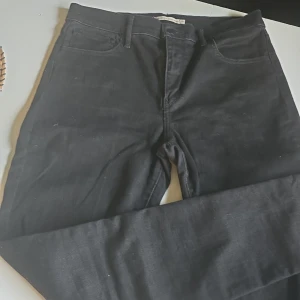 Levi's Premium 720 High Rise Skinny - Svarta Levi's Premium 720 High Rise Super Skinny jeans med hög midja och supertight passform. Klassisk femficksmodell i stretchigt jeanstyg som sitter snyggt och bekvämt. Perfekta svarta jeans för dig som gillar en slimmad siluett.