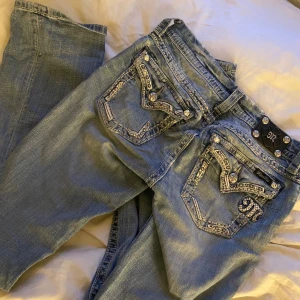 Miss Me ljusblå jeans med bootcut - Säljer ett par ljusblå jeans med bootcut från Miss Me med snygga detaljer och bling på bakfickorna. Jeansen har bootcut stil och coola broderier samt nitar och stenar på fickorna. Klassisk femficksmodell med låg midja och dragkedja. Storleken är 29, de är använda ett fåtal gånger så de är i väldigt fint skick!❤️Köptes för 1299 kr😌