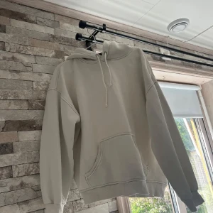Vit  hoodie från BikBok - Säljer en  vit hoodie från BikBok i storlek S. Tröjan har huva med snörning, magficka och ribbade muddar vid ärmslut och nederkant. Perfekt för en chill och avslappnad stil.