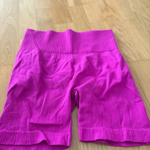 Ribbstickade cykelshorts i rosa - Säljer ett par ribbstickade cykelshorts i stark rosa färg. De är högmidjade och har en tight passform med bred resår i midjan. Materialet är stretchigt och består av 92% polyamid och 8% elastan, perfekt för träning eller chill. De sitter väldigt bra på rumpan, det är strech på rumpan. 
