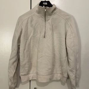 Beige half zip sweatshirt från Gina Tricot - Säljer en beige sweatshirt från Gina Tricot med half zip och hög krage. Tröjan har långa ärmar, ribbade muddar och en relaxed passform. Perfekt för lager-på-lager och chill dagar.