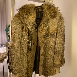 Beige pälsjacka - Säljer en pälsjacka med stora fluffiga slag och knappar framtill. Jackan har en mix av olika bruna och beige toner och ett mönstrat innerfoder. Perfekt statement-plagg för dig som vill sticka ut i vinterkylan. Litet hål pp sista bilden