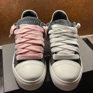 Numeris Atelier Pink Denim sneakers 44 - Snygga Numeris Atelier sneakers i storlek 44 med cool denimlook och slitna detaljer. Skorna har vit tå och häl i skinn, samt breda snören i både rosa och vitt för en unik stil. Perfekta för dig som vill sticka ut med en mix av street och casual vibes.