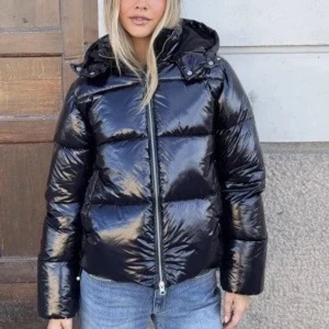 Svart glansig pufferjacka med huva - Svart pufferjacka med glansig finish och huva. Jackan har breda, quiltade sektioner och dragkedja framtill. Perfekt för kalla dagar och ger en cool vibe till din outfit. Passformen är normal och jackan har långa ärmar.