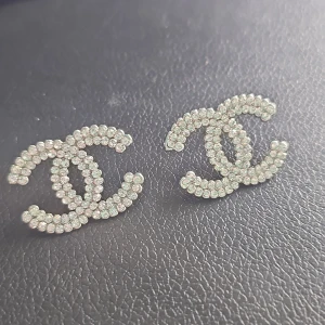 örhängen med strass - Snygga örhängen i klassisk CC-logga, täckta med glittrande strass. De är silverfärgade och har en lyxig vibe som verkligen sticker ut. Perfekta för dig som vill ha något extra till din look och älskar statement-smycken.