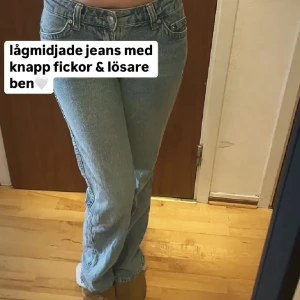 Lågmidjade ljusblå jeans med knappfickor - Ljusblå jeans med låg midja och lösare ben. Byxorna har knappfickor bak och klassisk femficksdesign framtill. Perfekta för dig som gillar en avslappnad och trendig look.