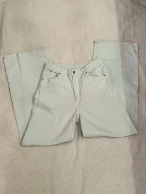 Wide jeans med raka ben från H&M - Snygga jeans med bred passform och raka ben. Jeansen ska egentligen vara i vit färg men har blivit ljusblåa efter tvätten. Jeansen har en klassisk femficksmodell med knapp och dragkedja framtill. Perfekta för en avslappnad och trendig stil.