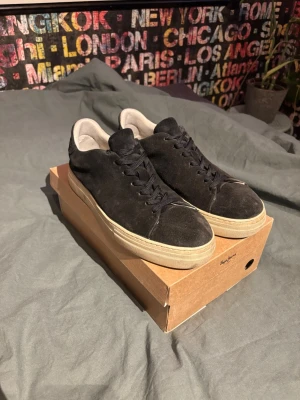 Svarta sneakers i mocka - Stilrena svarta sneakers med ovandel i mocka och vita sulor. Skorna har klassisk snörning och en låg profil. Insidan är ljus och ger en snygg kontrast till det mörka yttre. Perfekta för en avslappnad och trendig look. Storlek 43. Billigare vid snabb affär. Tvättas innan jag fraktar 