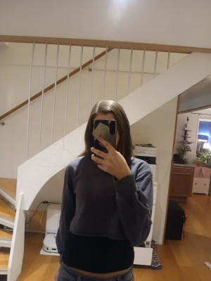 Mörkgrå cropped hoodie - Snygg mörkgrå cropped hoodie med långa ärmar och avslappnad passform. Perfekt för en chill och trendig look. Passar till jeans eller mjukisbyxor. Klassisk design utan synligt märke.