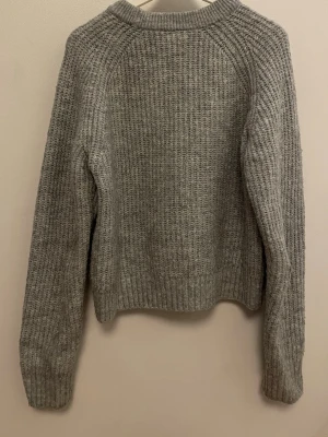 Grå stickad tröja - Jättefin grå stickad tröja med rund hals och långa ärmar. Tröjan har en grovstickad struktur och ribbade muddar vid ärmslut och nederkant💗 från Lindex, strl 146/152, använd fåtal gånger. Skriv vid frågor! Kan skicka flera bilder och diskutera pris! 