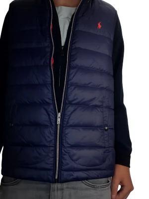 Vändbar dunväst från Polo Ralph Lauren - Snygg vändbar dunväst från Polo Ralph Lauren med ena sidan i marinblått och andra i rött. Västen har dragkedja, två fickor med knappar och ikonisk logga på bröstet. Perfekt för lager-på-lager och att hålla värmen med stil. Storlek 164-170