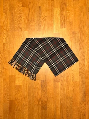 Grå Burberrry halsduk - Säljer en grå halsduk från Burberry. Halsduken är i gott skick och är gjord i 100% lamull. Var inte rädd för några frågor. Pris diskuteras inte!