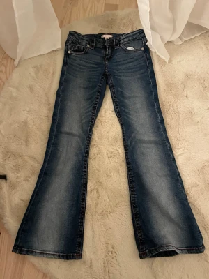 Gina tricot lowrise flare jeans  - Jeansen är i jätte bra skick knappast använda. Storlek 152. De har vinröda detaljer och kan dras åt i midjan. Köpta för 360kr och säljs för 200kr då de nästan aldrig blivit använda.