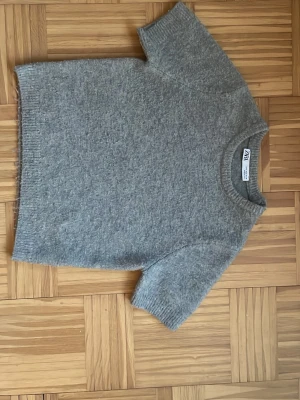 Grå stickad t-shirt från Zara - Stickad tröja från zara i storlek S men skulle säga att den mer är som XS, inga fläckar eller hål men nopprig💗💗💗
