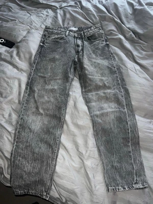 Grå '90s wide jeans från Bershka - Säljer ett par gråa '90s wide jeans från Bershka med tvättad look och raka ben. Jeansen har hög midja och bred passform för en avslappnad vibe. Klassisk femficksmodell och tillverkade i denim. Perfekta för dig som gillar retrostil.