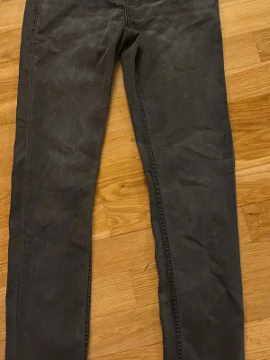 Levi's 512 Slim Taper grå jeans - Snygga grå Levi's 512 Slim Taper jeans med smal passform och avsmalnande ben. Klassisk femficksmodell med bälteshällor och knappgylf. Perfekta för dig som gillar en modern och stilren look. Storlek 14a. Bara höra av sig vid funderingar 