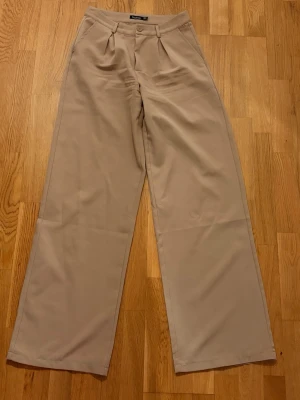 Beiga vida kostymbyxor - Stilrena beiga kostymbyxor med hög midja och vida ben. Säljer då dem ej används längre