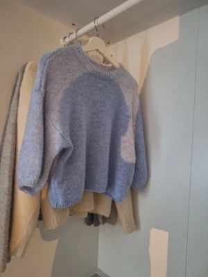 Ljusblå stickad tröja - Mysig ljusblå stickad tröja med rund halsringning och avslappnad passform. Tröjan har ribbstickade muddar vid ärmslut och nederkant. Perfekt för lager-på-lager och enkel att styla till olika outfits.