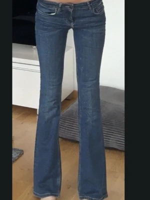 Blå bootcut jeans i storlek 34 - Snygga blå bootcut jeans med klassisk femficksdesign och normal passform. Jeansen har en lätt utsvängd benform och är tillverkade i ett mjukt denimtyg som sitter skönt på kroppen. Perfekta för dig som gillar en tidlös och trendig look.