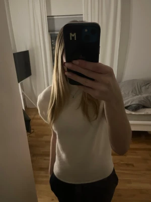 Vit ärmlös stickad tröja - Säljer en vit, ärmlös stickad tröja med rund hals. Tröjan har en mjuk och lite lös passform, Materialet är ull eller en ullmix. Använd 1 gång!