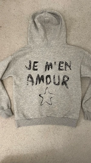 grå je m’en amour hoodie - säljer en superfin hoodie med ”je m’en amour” tryck på från gina. den är i strl 134/140,  och den är bara använd ett fåtal gånger så den är i mycket bra skick❣️