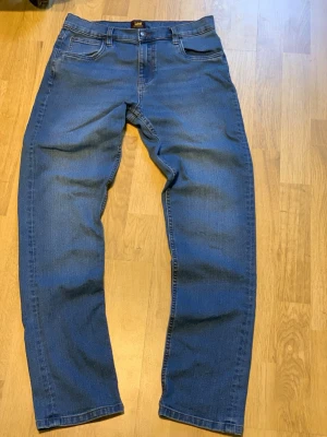 Blå raka jeans från Lee, Luke - Snygga blå jeans från Lee med klassisk femficksdesign och normal passform. Jeansen har rak siluett och är gjorda i tåligt bomullsjeansmaterial. Perfekta för en clean och tidlös look.